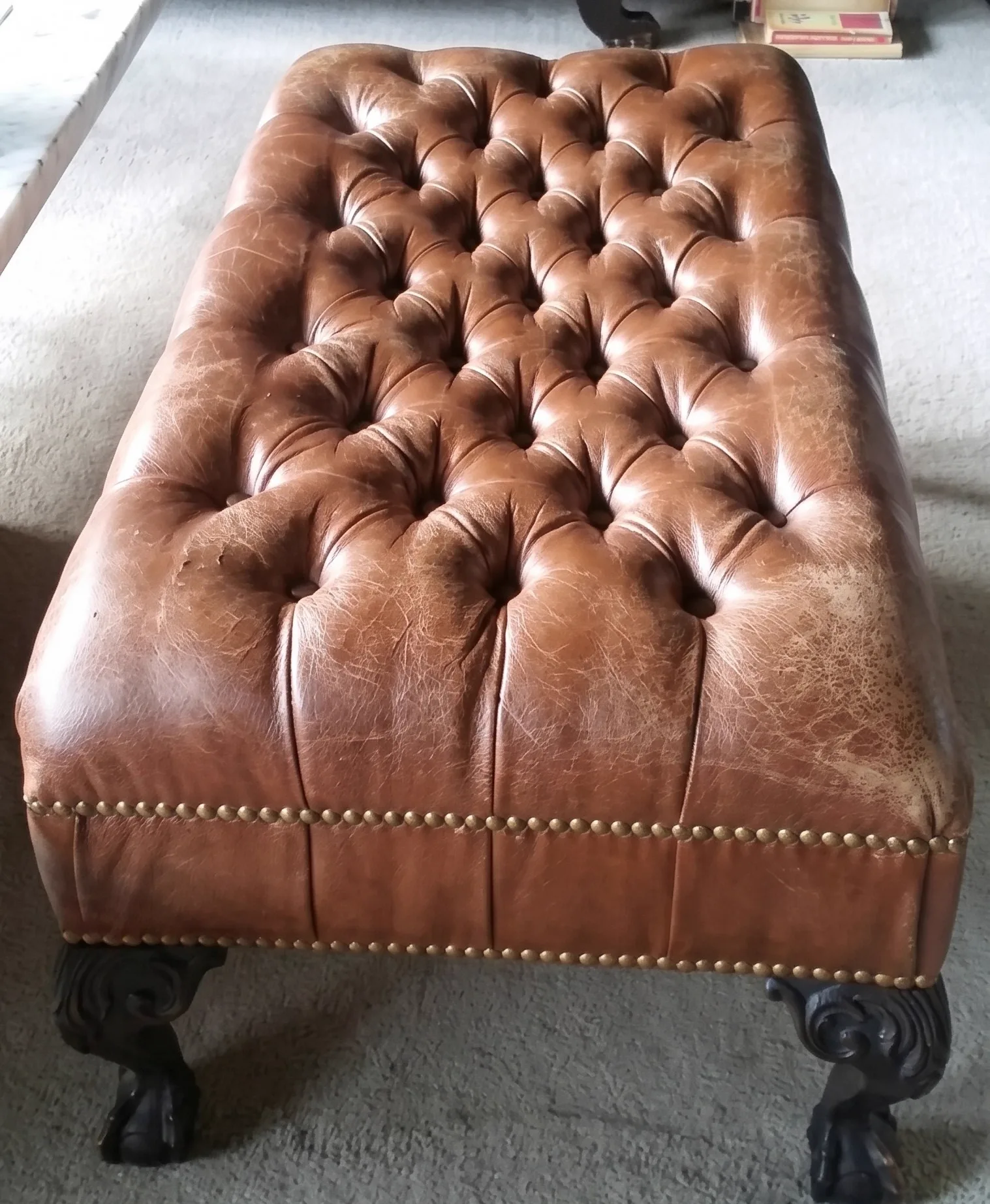 Worn, cracked tan buttoned Chesterfield ottoman before restoration